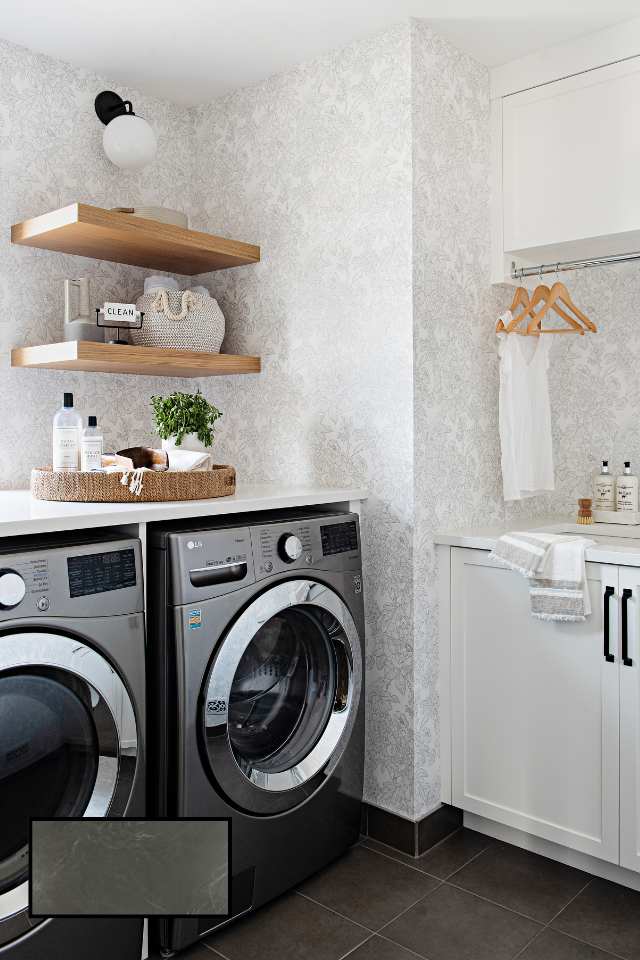 wallpapered laundry room with open wood shelves and dark tile floors